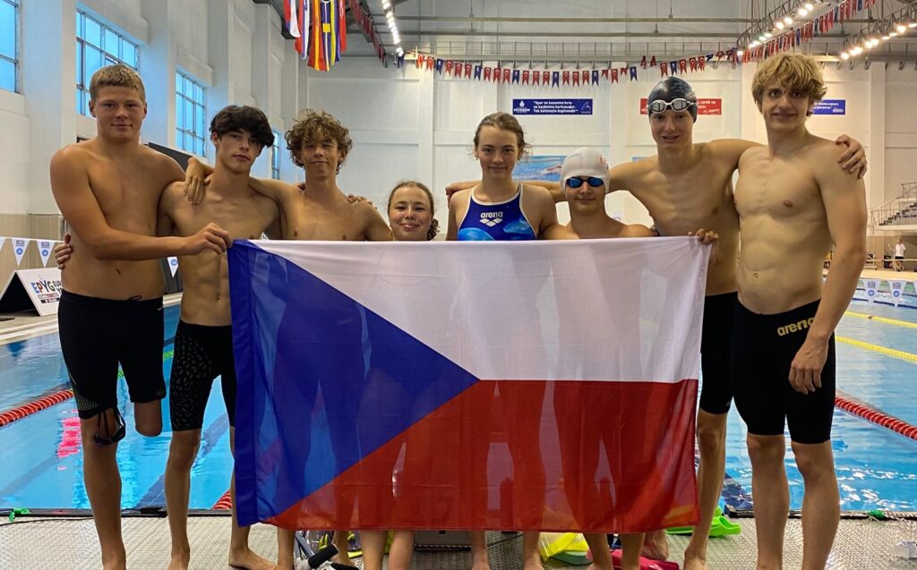 Obrázek juniorských reprezentantů do 18 stojících u bazénu. David Kratochvíl, Jakub Vaněk, Eduard Prokop, Vojtěch Vrbický, Matěj Staša, Václav Mikolin, Alexandra Borská a Nela Zdenka Kuiper.